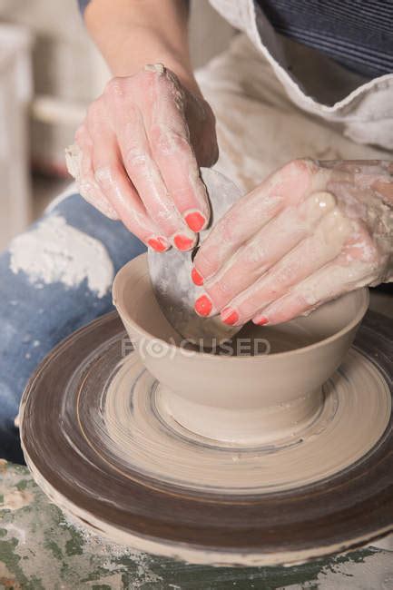 Close up of a woman's hand shaping pottery clay on a pottery wheel in a ceramic workshop ...