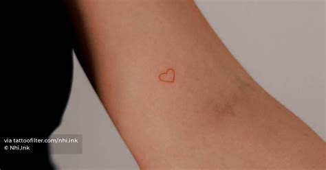 Minimalistic red heart tattoo located on the inner arm.