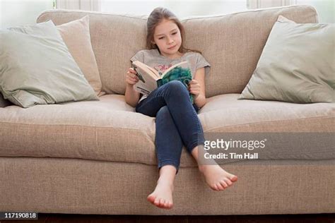 Barefoot Girl Reading Book On Couch Stock-Fotos und Bilder - Getty Images