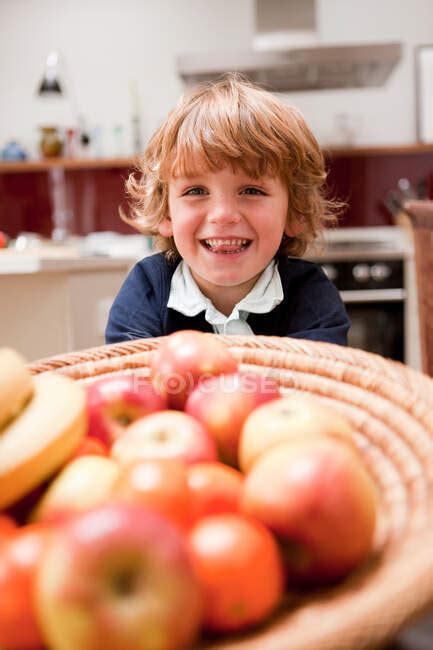Young boy sitting at dining table with apples — rosy, kitchen - Stock Photo | #165290024