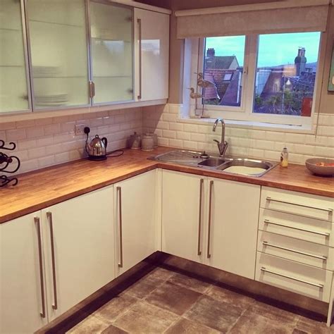 a kitchen with white cabinets and wooden counter tops