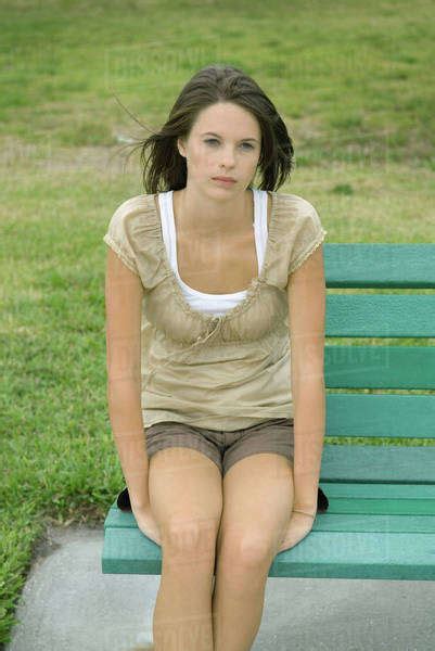 Teenage girl sitting on bench, looking away - Stock Photo - Dissolve