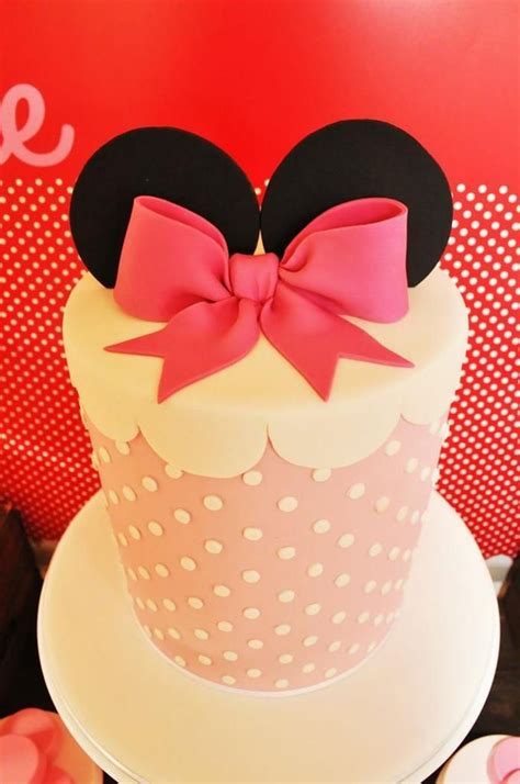 a minnie mouse cake with pink and white polka dot icing, topped with a bow