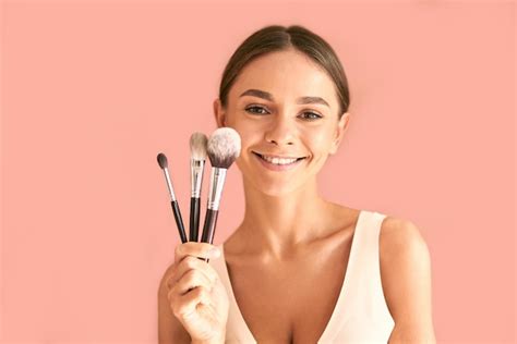 Premium Photo | Beautiful young woman without makeup holding several makeup brushes and smiling