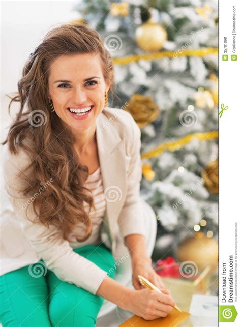 Smiling Young Woman Singing Envelope in Front of Christmas Tree Stock Photo - Image of luxury ...
