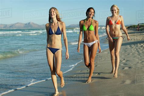 Women in bikinis walking on beach - Stock Photo - Dissolve