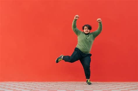 Premium Photo | Funny fat guy dancing on a red wall and listening to ...