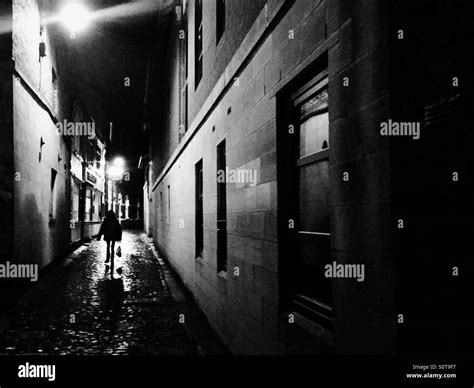 Woman walking down dark alley Stock Photo - Alamy