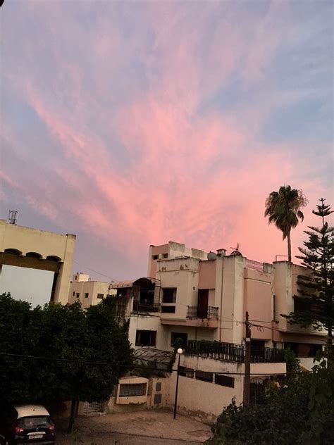 the sky is pink and blue as the sun sets in front of an apartment building