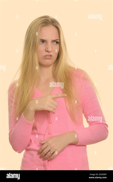 Studio shot of young beautiful teenage girl pointing finger and looking disgusted Stock Photo ...