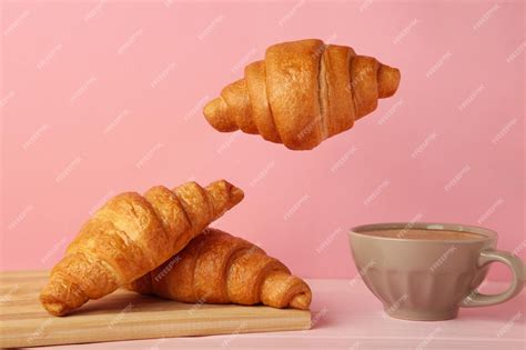 Premium Photo | Flying croissant with coffee on pink background