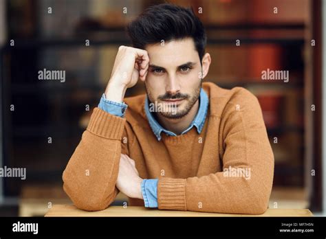 Spain, Andalusia, Granada. Attractive young man with modern hairstyle sitting in a coffee bar ...