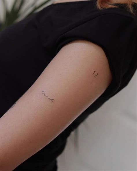 "Trust" and number "17" tattooed on the upper arm.