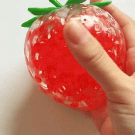 a hand is holding a plastic strawberry