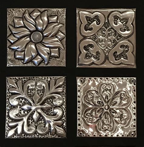 four square metal tiles with designs on them, all in different shapes and sizes to choose from