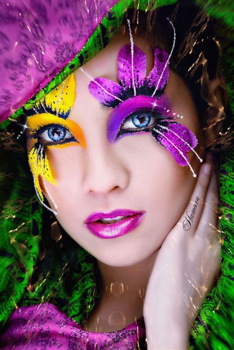 a woman with purple and yellow makeup is posing for the camera, her hand on her face