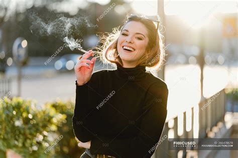 Pretty woman smoking cigarette on sunny street — rest, nicotine - Stock Photo | #266478678