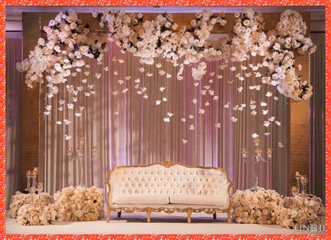 a couch sitting under a flower filled canopy in front of a stage with flowers hanging from the ...