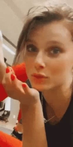 a woman is brushing her hair with an orange blow dryer