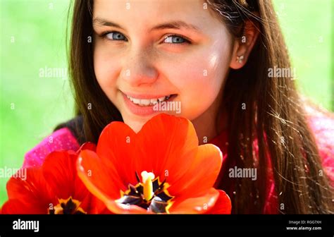 Flowering in spring. Cute girl child with red tulip flowers in spring day. Pretty girl with ...