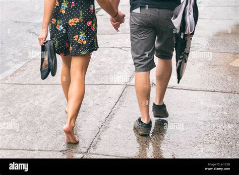 Couple on the street under the rain, woman walking barefoot Stock Photo - Alamy