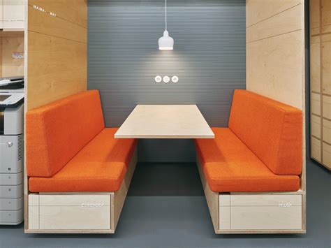 an orange couch sitting next to a white table in a room filled with cabinets and drawers