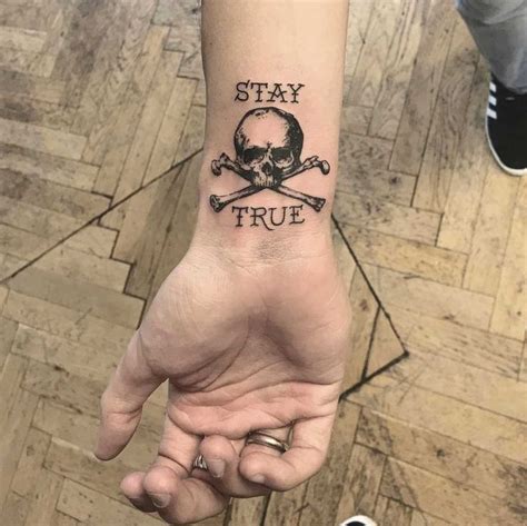 Skull and crossbones with the words ‘stay true’ tattooed on the right wrist by tattooist Annelie ...