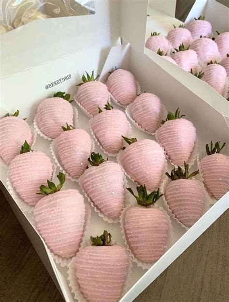 a box filled with pink strawberries sitting on top of a wooden table next to other boxes