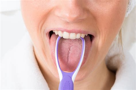 Woman Using Tongue Cleaner - Flenniken Dental Blog