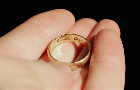 A man holds a wedding ring engraved "with love" - ShaadiWish