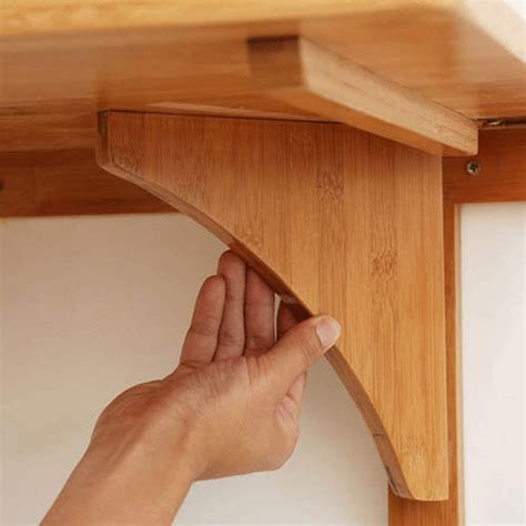 a hand is holding the edge of a wooden shelf