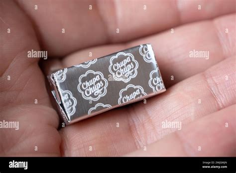Close-up view of square shape Chupa Chups candy on the palm of the human hand, wrapped in silver ...