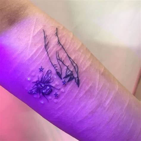 a small tattoo on the arm of a woman with flowers and stars around her wrist