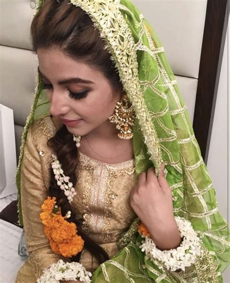 a woman wearing a green and gold outfit with flowers in her hair sitting on a chair