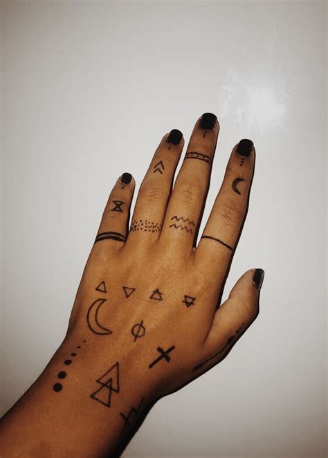a person's hand with tattoos on it and other symbols painted on the palm