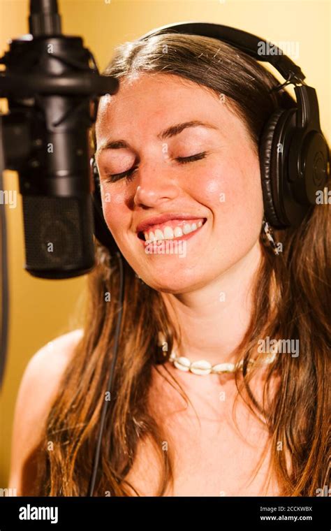 Singer with headphones at microphone in recording studio Stock Photo - Alamy