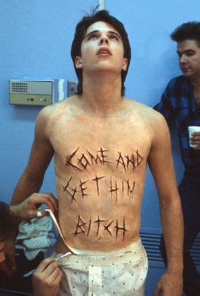 a shirtless man with some writing on his chest in a room next to other men