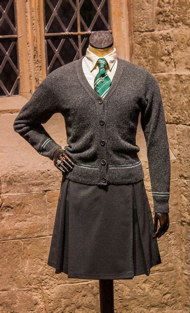 a mannequin dressed in a kilt stands next to a stone wall and window