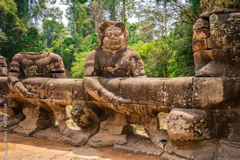 Preah Khan temple, Cabodia: Sculpture of demon holding serpent Vasuki on causeway with railings ...