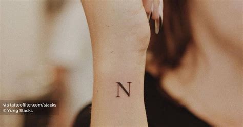 Minimalist letter "N" tattoo on the wrist.