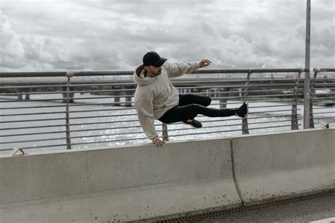 Man in White Long Sleeve Shirt and Black Pants Jumping on White Concrete Fence · Free Stock Photo