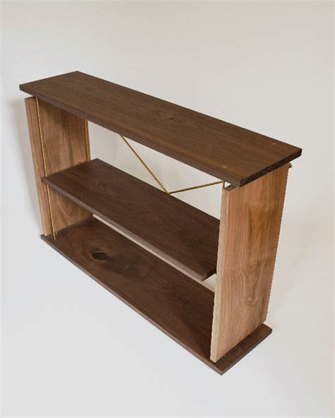 a wooden shelf with two shelves attached to the top and bottom, on a white wall