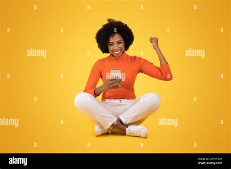 A joyful young woman with natural curly hair celebrates a victory with a fist pump Stock Photo ...