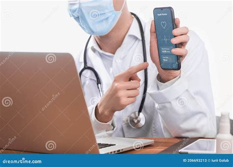 Doctor Having a Video Call on a Laptop and Showing an App on His Phone ...