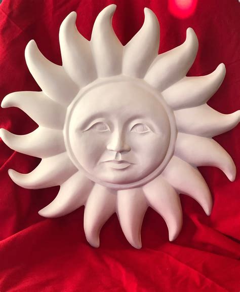 a ceramic sun face sitting on top of a red cloth