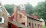 Color photograph of partially photographed stone buildings, one with white window shutters and ...