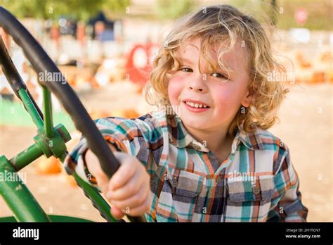 Adorable Young Boy Playing on an Old Tractor in a Rustic Outdoor Fall Setting Stock Photo - Alamy