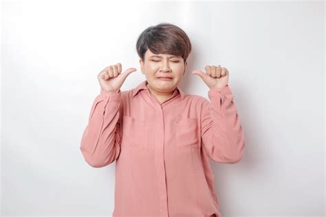 Premium Photo | Excited shorthaired asian woman wearing pink shirt gives thumbs up hand gesture ...