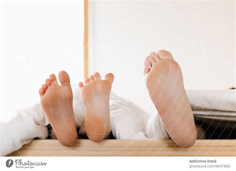 Unrecognizable siblings lying barefoot in bed - a Royalty Free Stock ...