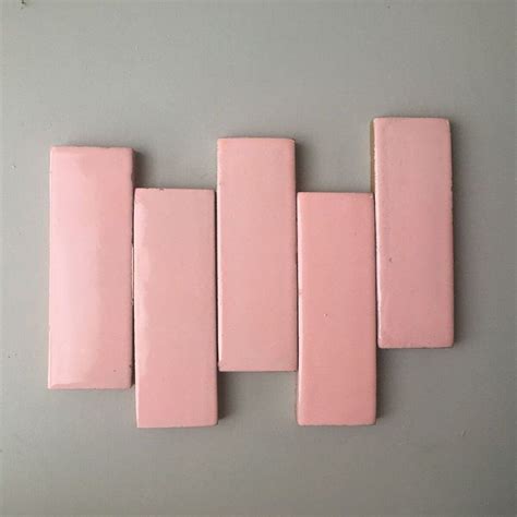 five pink tiles are arranged on the wall